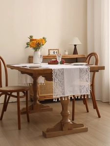 Detailed texture of white lace table runner with hollow floral embroidery and tassels