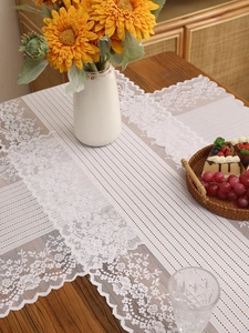 Close-up of white lace table runner with rose jacquard patterns on wooden table
