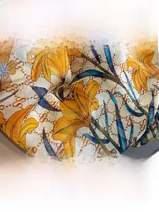 Close-up of elegant silk scarf showing yellow lily prints and fine fabric texture