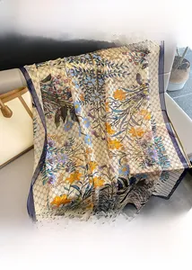 Detailed botanical print on long silk scarf with blue border and monogram pattern