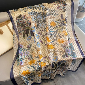 Detail view of floral print scarf with SS jacquard pattern on a grey leather sofa