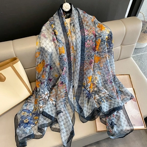 Detailed view of lightweight floral monogram chiffon scarf draped on a leather sofa