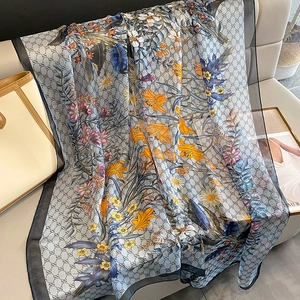 Detailed texture of lightweight floral scarf with monogram pattern on cream leather sofa
