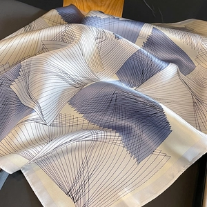 Close-up of a silk scarf featuring geometric line patterns and soft purple gradients