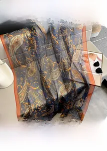 Detailed view of blue paisley long scarf with orange border on a lounge sofa
