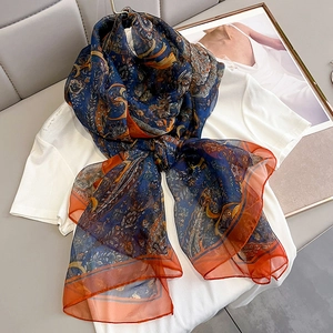 Detail of paisley print scarf with deep blue and orange patterns on chiffon fabric