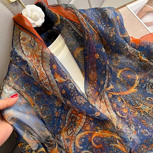Detail of navy blue paisley silk scarf with orange borders and bohemian floral patterns
