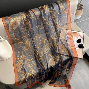 Detail of navy blue paisley print scarf with orange border and translucent texture