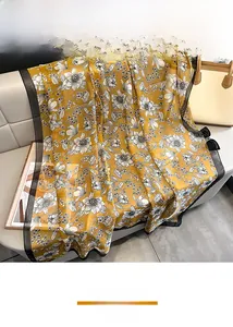 Detailed shot of yellow floral silk scarf with botanical print and black border on a sofa