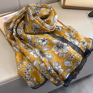 Close-up of yellow silk scarf featuring hand-drawn floral sketches and sheer black trim