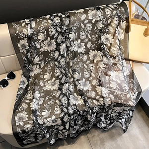 Detail of floral print summer shawl draped on a sofa with fashion accessories