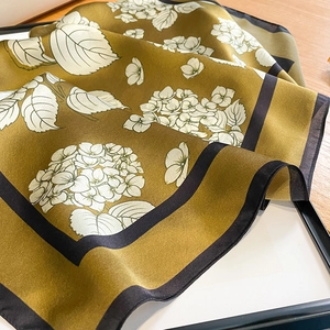 Detail of silk scarf with white hydrangea print on olive gold fabric and black borders