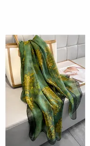 Detail of dark green printed silk scarf on tote bag showing soft sand fabric texture