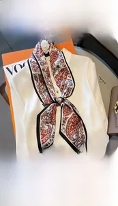 Detailansicht eines schmalen Seidenschals mit Paisley-Muster an einem Hemdkragen