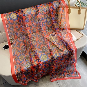 Floral print silk scarf with red border on sofa with fashion accessories