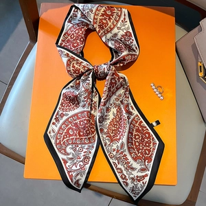 Roter schmaler Seidenschal mit Paisleymuster und Perlenring auf orangefarbenem Hintergrund