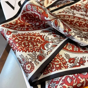 Detail eines Seidenschals mit rotem Paisley-Muster und schwarzer Naht auf Modemagazin