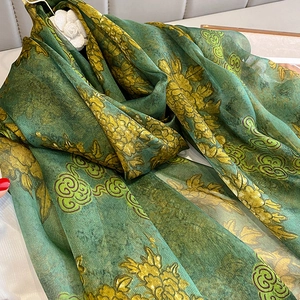 Detail of silk scarf with gold floral patterns on dark green satin fabric close-up