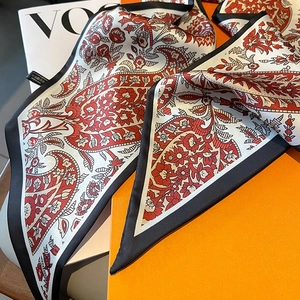 Detail eines schmalen Seidenschals mit Paisley-Muster neben einem Modemagazin