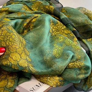 Close-up of green floral silk scarf with yellow flowers and black sheer trim edges