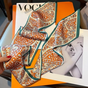 Detail eines Seidenschals mit Paisley-Muster auf Magazin und orangefarbener Box