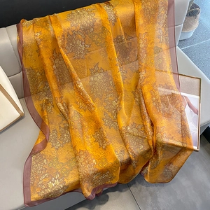 Close-up of floral print silk scarf in orange with elegant drape and satin texture