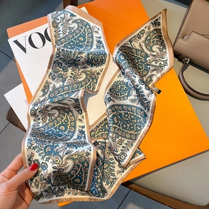 Detailaufnahme des schmalen Schals mit Paisleymuster auf einer orangefarbenen Geschenkbox