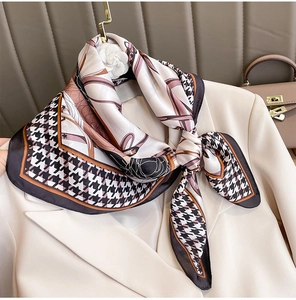 Dettaglio di un foulard in seta pied-de-poule annodato su un blazer beige elegante