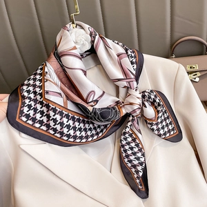 Elegante foulard in seta pied de poule annodato su un blazer beige raffinato