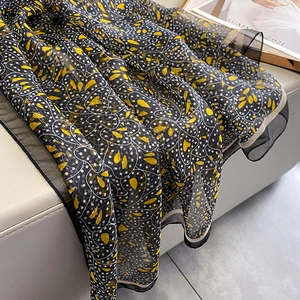 Detail of floral chiffon scarf featuring yellow hearts and white dots on black fabric