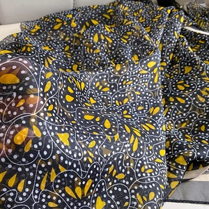 Detail of floral print scarf showing lightweight black fabric with yellow patterns