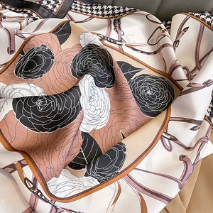 Dettaglio foulard in seta con stampe di camelia, cinture equestri e bordo pied-de-poule