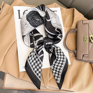 Dettaglio di un foulard di seta con pied de poule e fiori su un trench beige