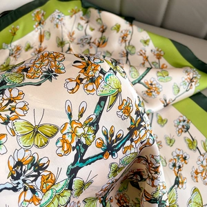 Foulard en soie à fleurs avec papillons et bordure verte présenté en drapé doux