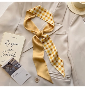Detail of a ginger yellow gingham silk scarf tied on a beige blazer with floral patterns