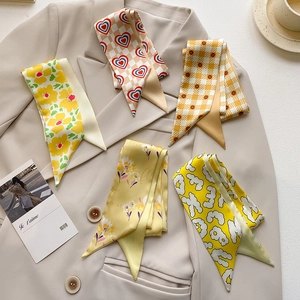 Detail of five narrow silk scarves with floral patterns displayed on a beige blazer suit