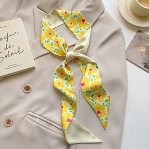 Detail of floral skinny scarf tied on a beige blazer with elegant book and coffee cup