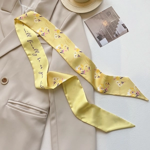 Detail of yellow floral skinny silk scarf with cursive text on beige blazer