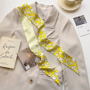 Detail of yellow narrow printed silk scarf paired with a beige blazer for stylish outfit