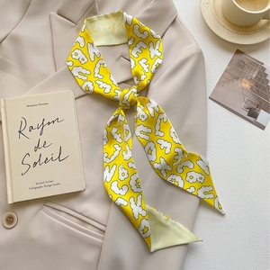 French style bright yellow printed silk twilly scarf knotted on a beige suit lapel