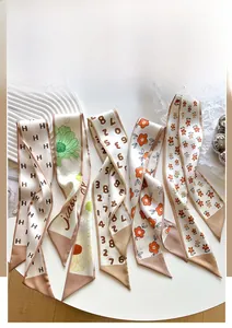 Detail of silk-feel twilly scarves set with H letter motifs and floral prints in khaki