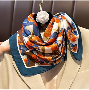 Detail of silk scarf with orange floral pattern draped on a beige blazer collar