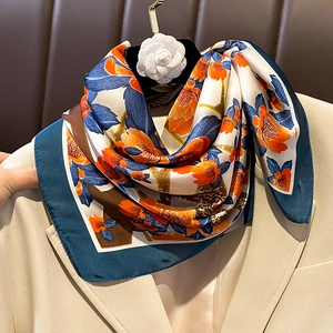 Elegant floral print silk scarf in orange and navy blue on a beige blazer jacket
