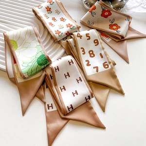 Detailed close-up of premium skinny silk scarves with floral and H-pattern prints