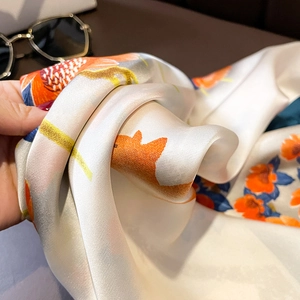 Detailed view of floral silk scarf fabric with elegant orange and blue flower print