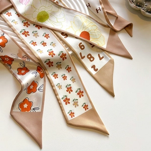 Close-up of premium satin silk scarves with floral prints and geometric letter patterns