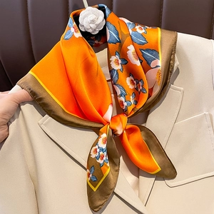 Elegant floral silk scarf tied in a bow on a beige blazer with camellia detail