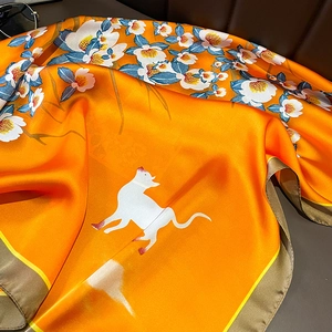 Detail of silk scarf showing orange floral pattern with satin finish and hand-rolled edges