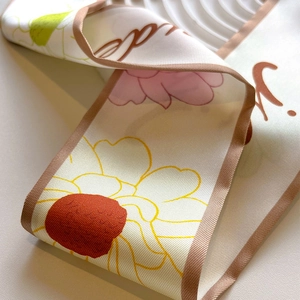 Macro shot of khaki twill silk scarf with floral patterns and contrast brown piping