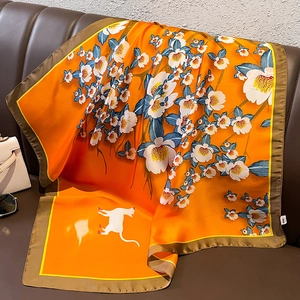 Elegant orange silk floral scarf with cat silhouette on a brown leather sofa